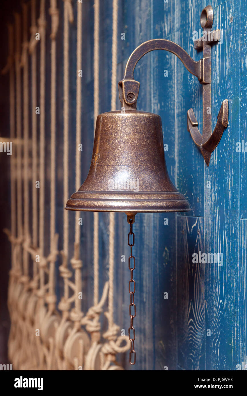 Tres viejas campanas de cobre vintage, el timbre de la puerta, cuerdas  sobre una pared azul de madera envejecida. Vista lateral. Concepto de  elemento de decoración en el interior de la cubierta,