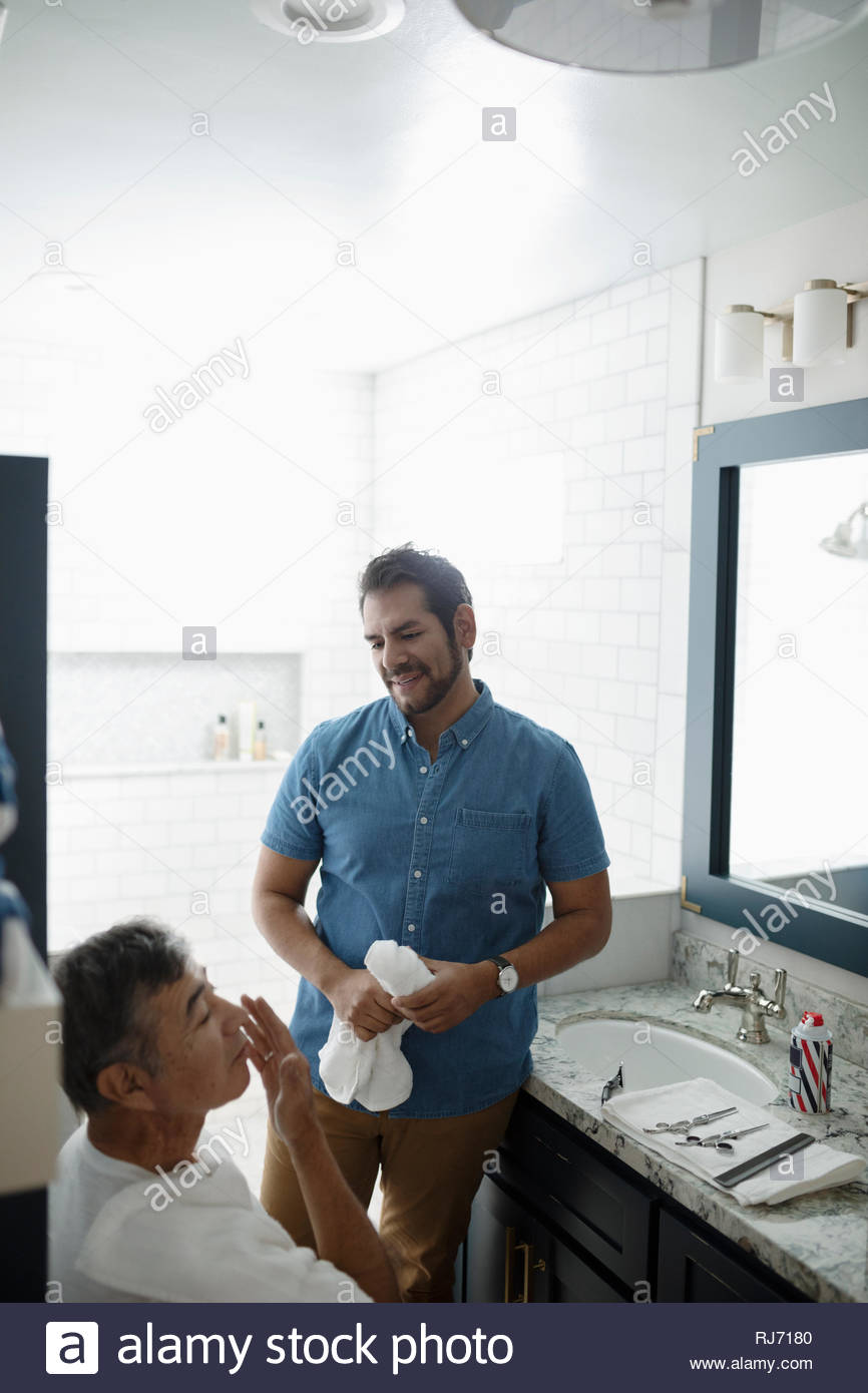 Hijo Latinx padre senior de afeitado facial en el baño. Foto de stock