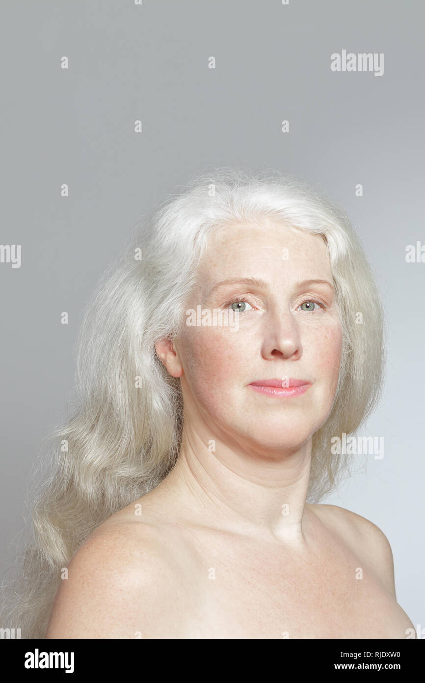 Retrato de una atractiva mujer madura con pelo largo gris hermoso delante de un fondo blanco, espacio de copia Foto de stock