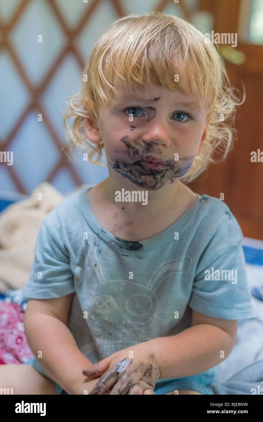 Un buen retrato de un chico encantador con un sucio rostro serio que acaba de comer una pastilla de carbón. Foto de stock