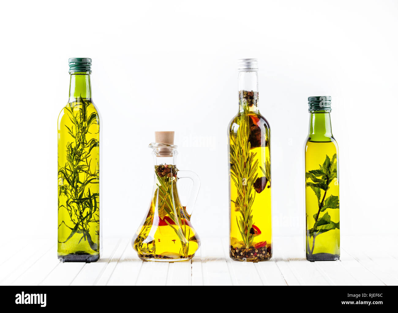 Botella de aceite casero con hierbas y especias sobre fondo blanco. Espacio libre para el texto. Foto de stock