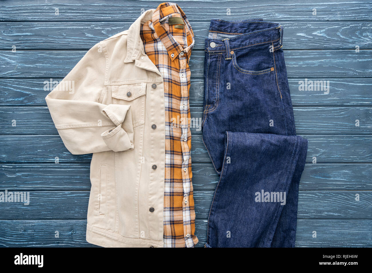 Vista superior de la camisa a cuadros, chaqueta y pantalones de mezclilla  sobre fondo de madera Fotografía de stock - Alamy