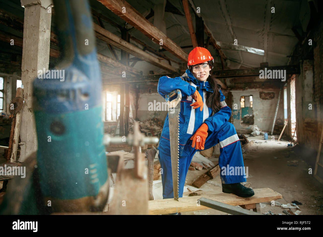 Destruir los estereotipos de género. Mujer con casco utilizando diferentes herramientas de trabajo masculino. La igualdad de género. Chica trabajando en remodelación plana. Construcción, reparación y renovación. La mujer en la profesión masculina Foto de stock