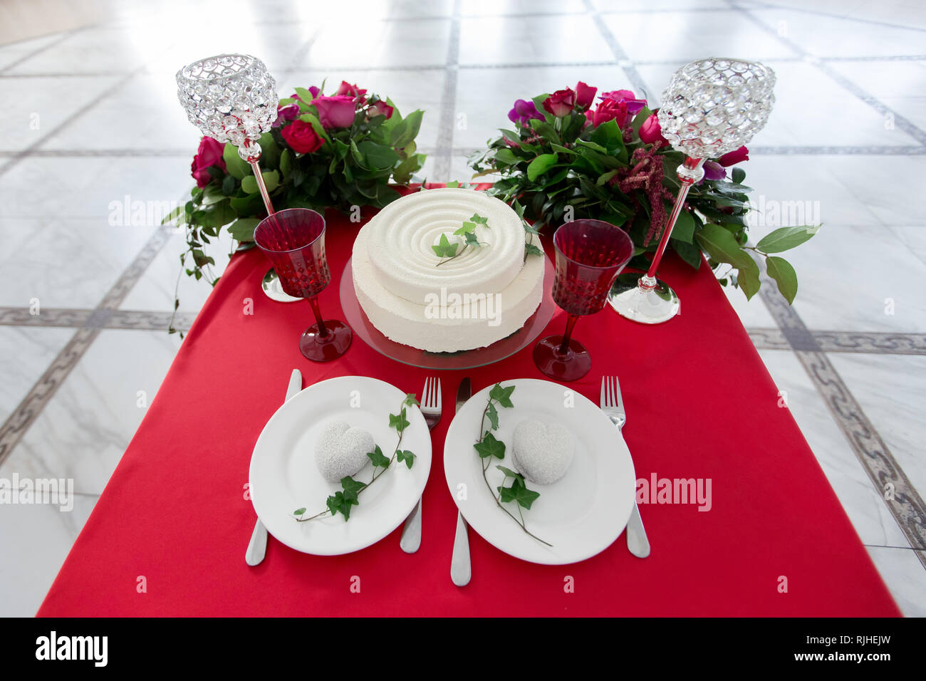 La decoración de la boda - Bodas mesa para dos. Pastel blanco, flores,  vasos de cristal en el cuadro rojo. vista desde arriba Fotografía de stock  - Alamy