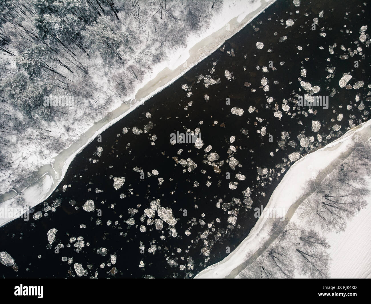 Vista a vuelo de pájaro de la congelación de río y bosque nevado de drone Foto de stock