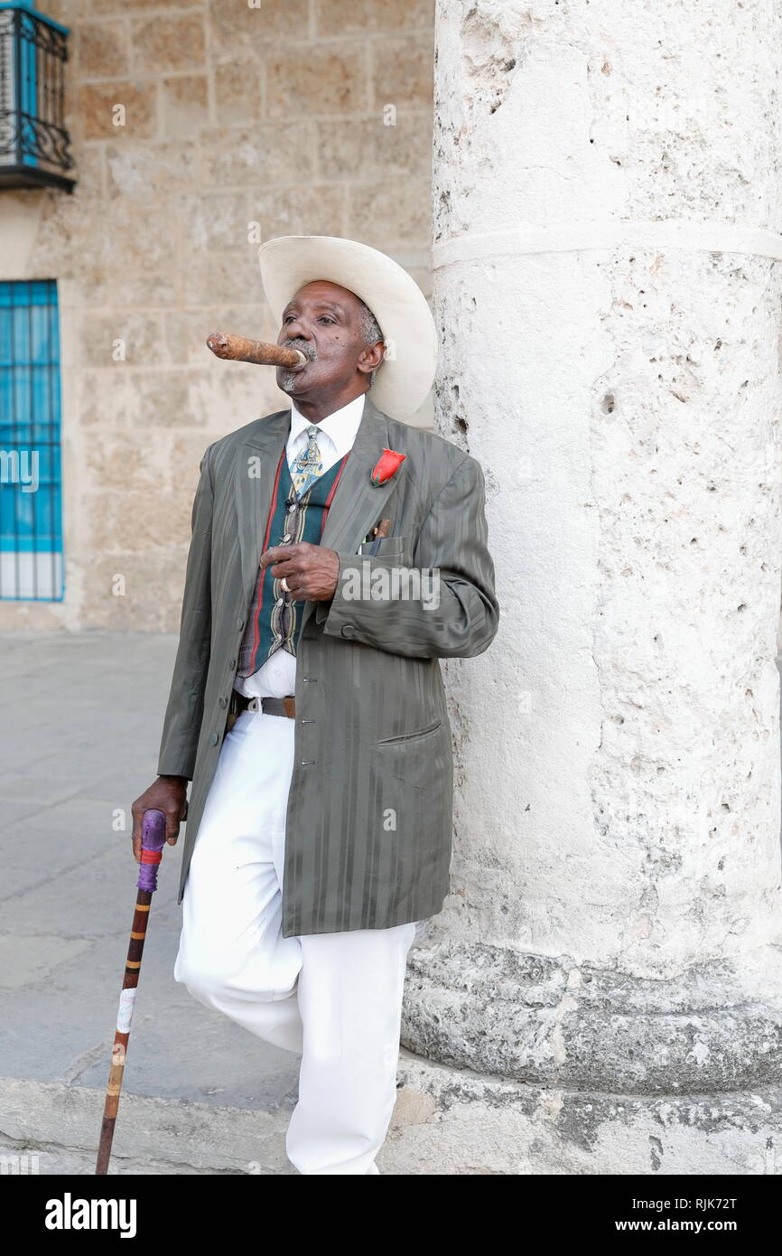 Plaza de la Iglesia, La Habana - Cuba - un hombre cubano sombrero cowboy blanco y elegante mirando los alrededores con cigarro en su boca de stock - Alamy