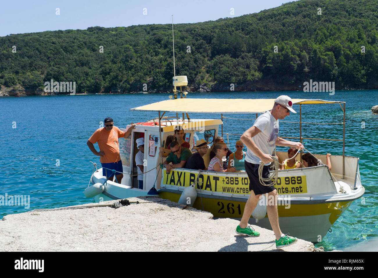 Un pequeño barco taxi ( ferry ) aterriza en el puerto de Valun village en la isla de Cres Croacia Foto de stock