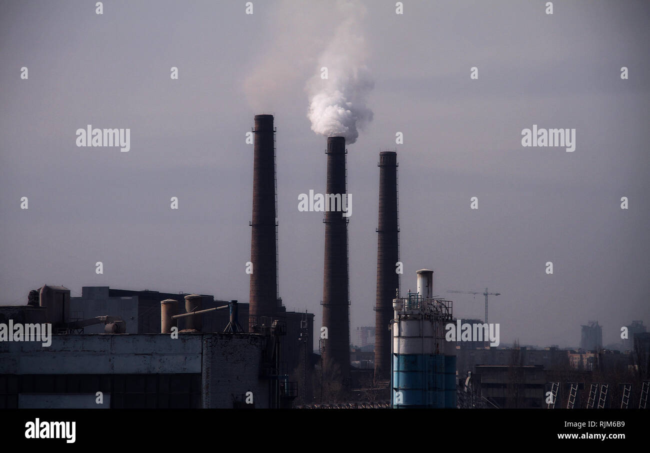 Chimeneas de fábricas industriales contaminando el aire bajo el smog en el cielo Foto de stock