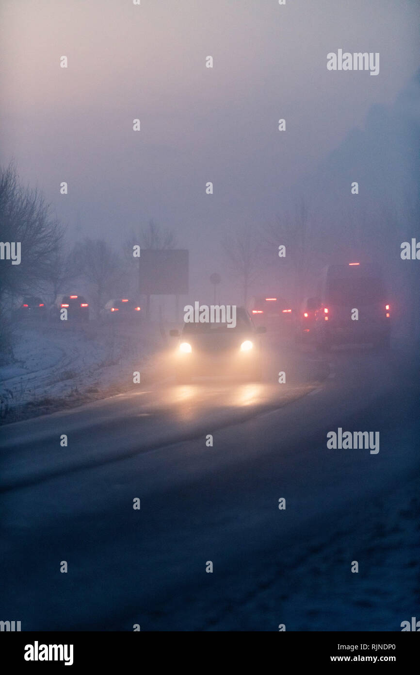 Luminosos de los faros de los coches en el crepúsculo de la niebla. Foto de stock