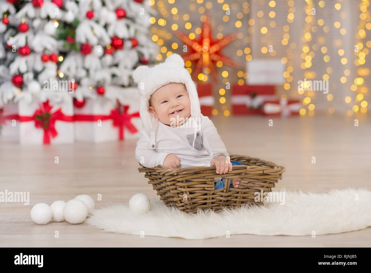 Hermoso pequeño baby boy celebra la Navidad. Las festividades de Nuevo. Bebé en traje de Navidad ropa casual con regalos en piel cerca de año nuevo Fotografía de stock -