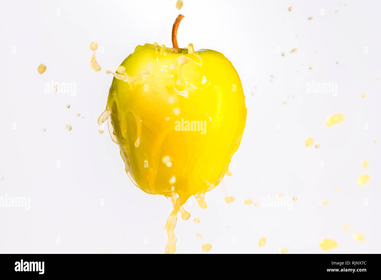 Manzana amarilla y salpicaduras de jugo fresco Foto de stock