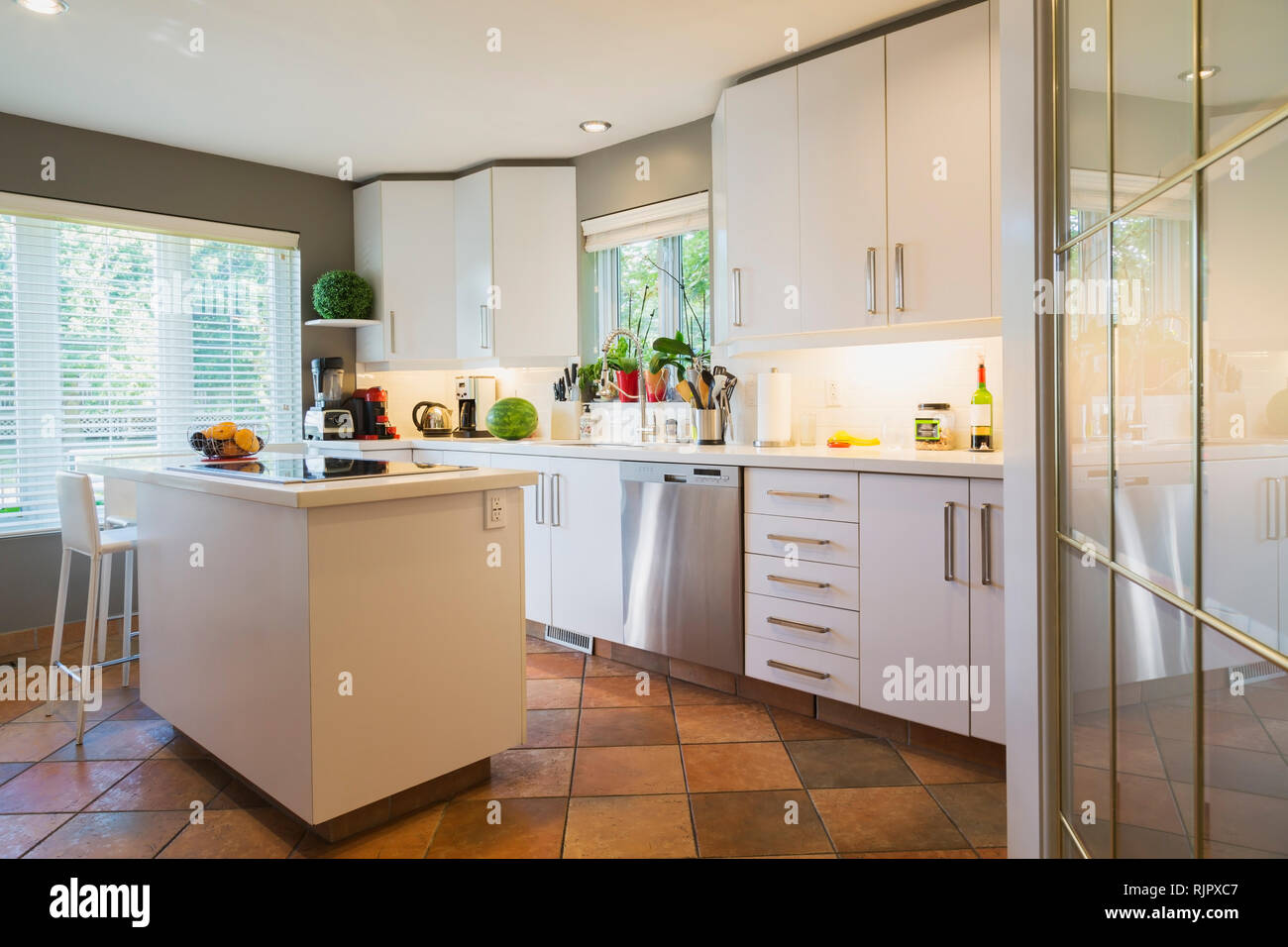 Alacenas blancas, encimera de cuarzo y la isla con encimera de vidrio y  espalda alta barstool en cocina Fotografía de stock - Alamy