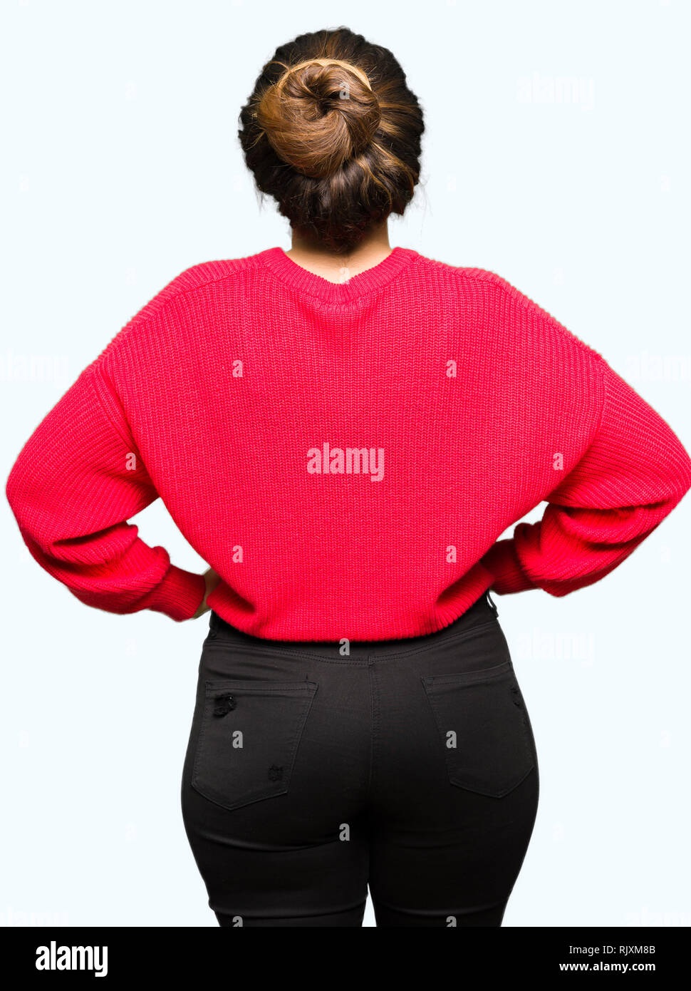 Hermosa joven mujer vistiendo remera roja y bun de pie mirando hacia atrás  lejos con los brazos sobre el cuerpo Fotografía de stock - Alamy