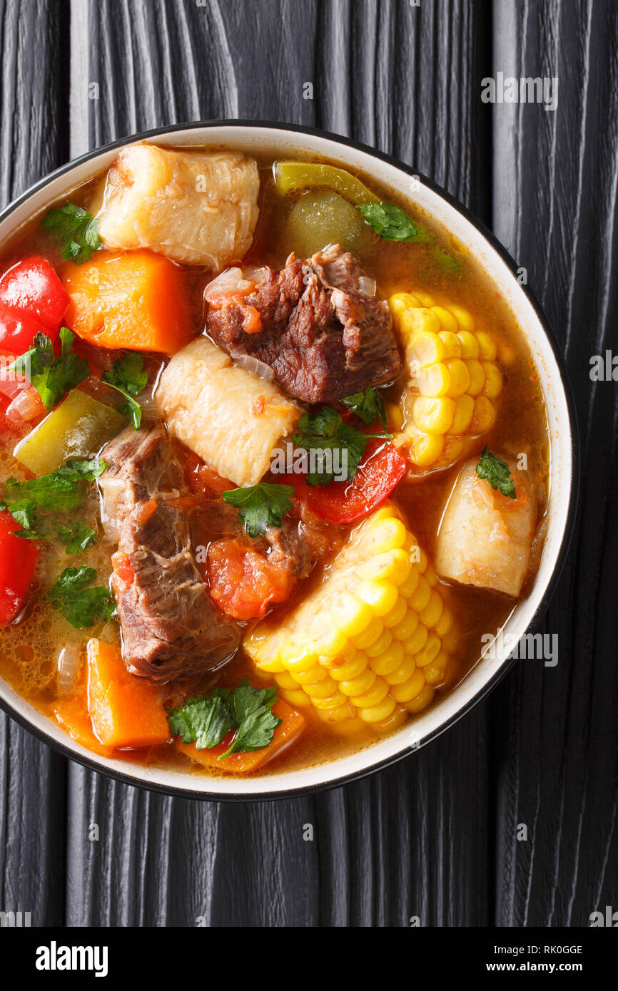 Sancocho Latinoamericano espesa sopa de carne con verduras de cerca en un plato sobre la mesa. Vertical superior vista desde arriba, estilo rústico Foto de stock