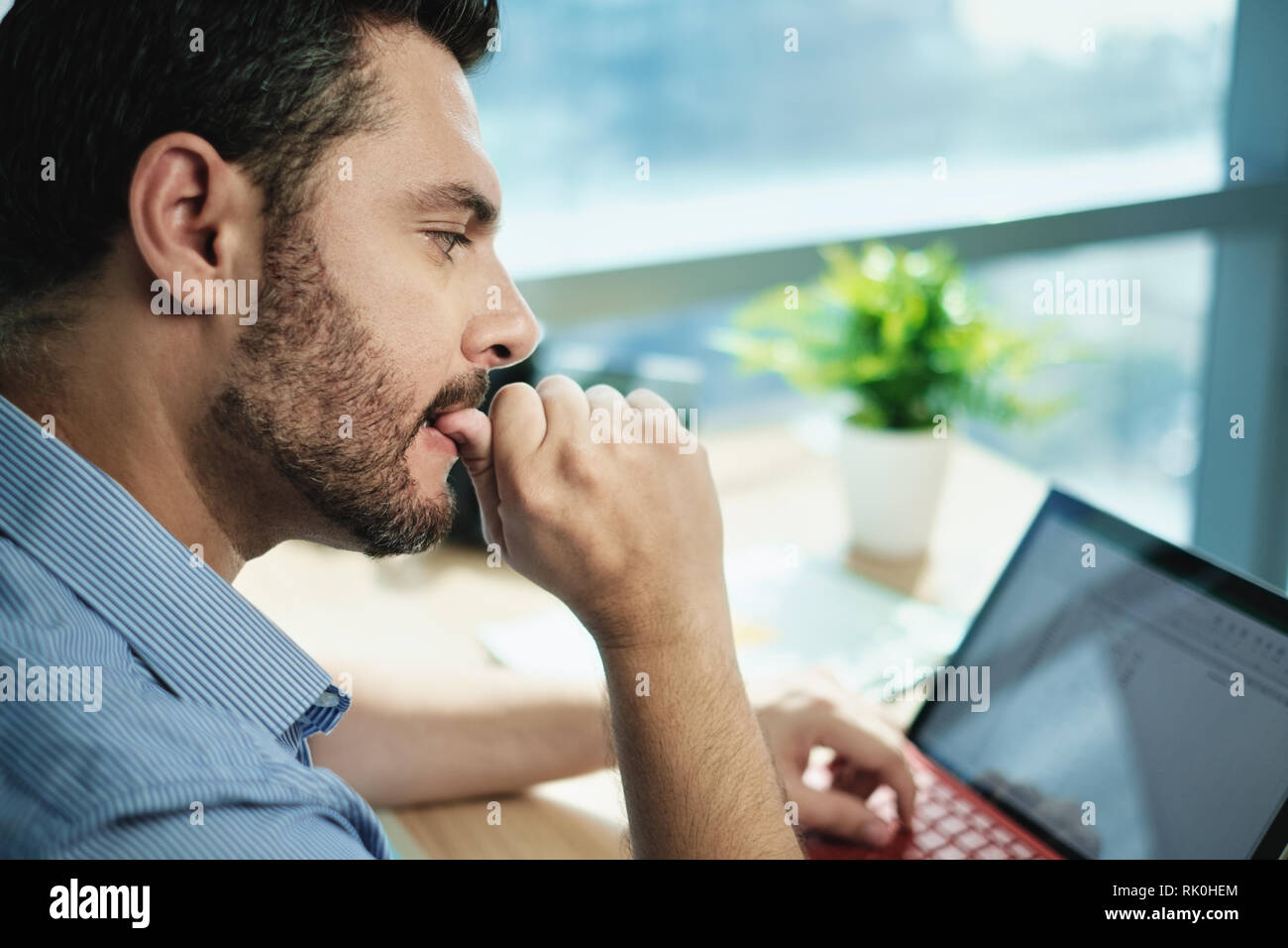 Empresario ansioso mordiendo las uñas que trabajan con ordenador portátil en la oficina Foto de stock