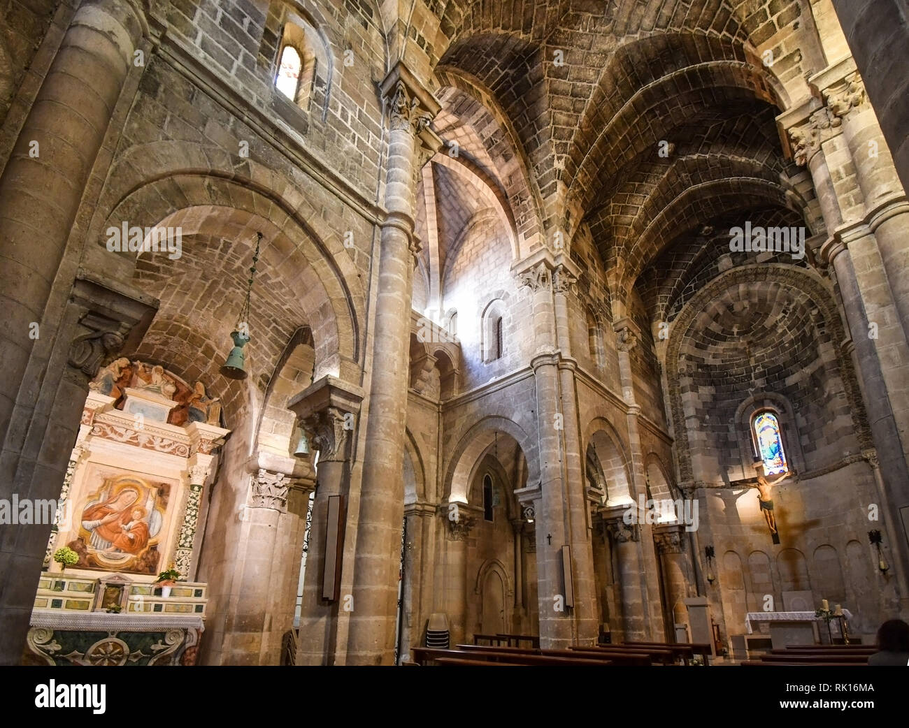 La nave interior y altar representando la crucifixión de Jesucristo iluminada por vidrieras en la iglesia parroquial de San Giovanni Battista en Mater Foto de stock