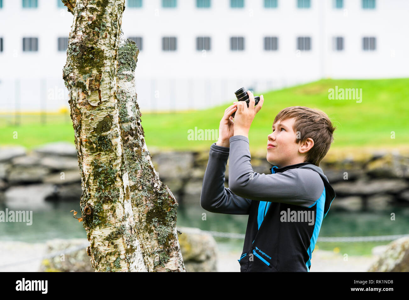 Cándido retrato de muchacho fotografiar árbol con cámara digital, imagen en color Foto de stock
