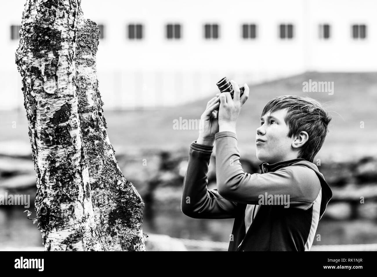 Cándido retrato de muchacho fotografiar árbol con cámara digital, imagen en blanco y negro Foto de stock