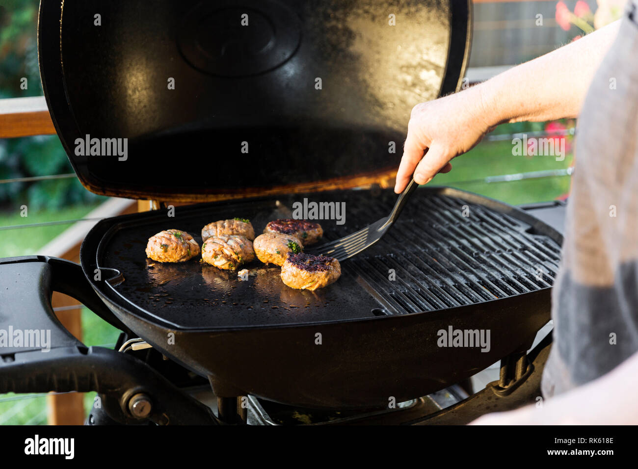 El hombre volteo burger en inicio configuración de barbacoa. Foto de stock