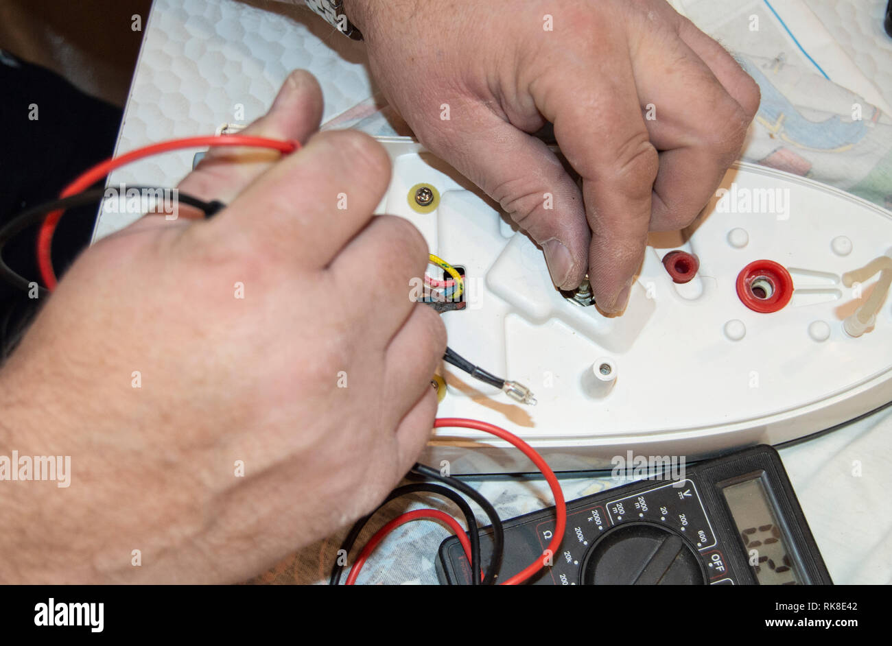 Cerca de la antigua mano de electricista, el uso del voltímetro digital  para la tensión para reparar la plancha eléctrica, el enfoque selectivo  Fotografía de stock - Alamy