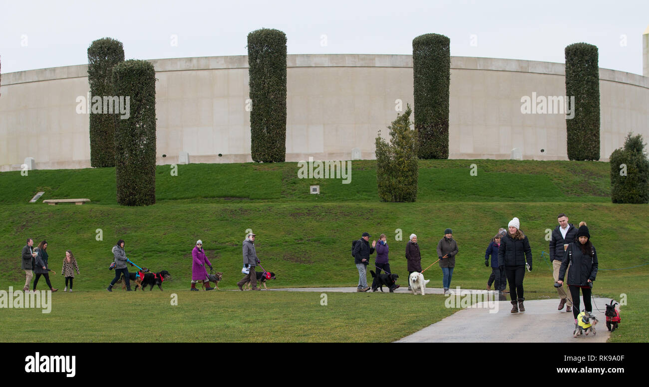 Los dueños de perros frente al Monumento a las Fuerzas Armadas como cientos de perros y sus dueños asisten al evento anual Paws for Remembrance del National Memorial Arboretum en Alrewas, Staffordshire. Foto de stock