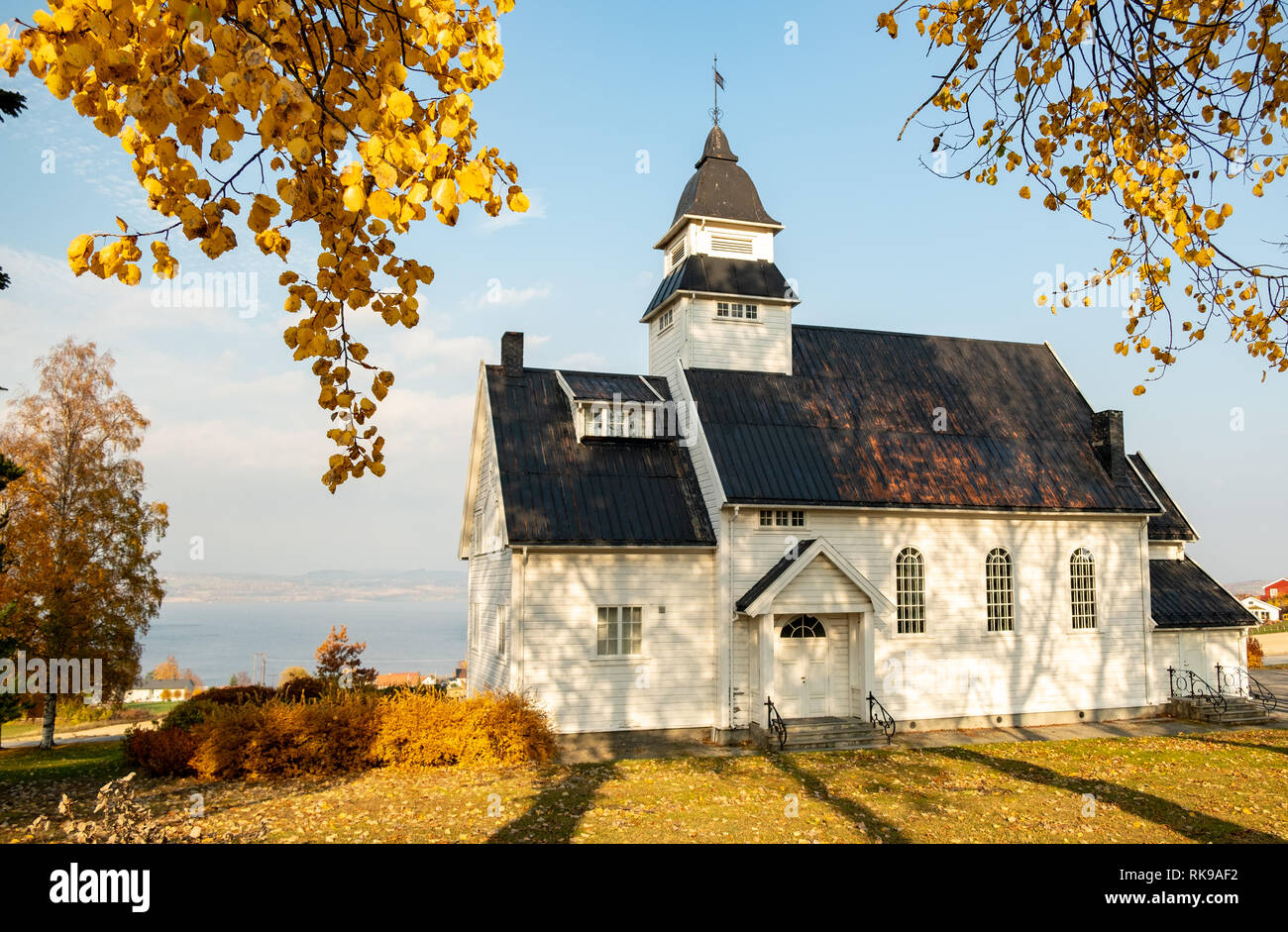 La pequeña iglesia de madera blanca tradicional en Kapp, Noruega con hojas de otoño Foto de stock