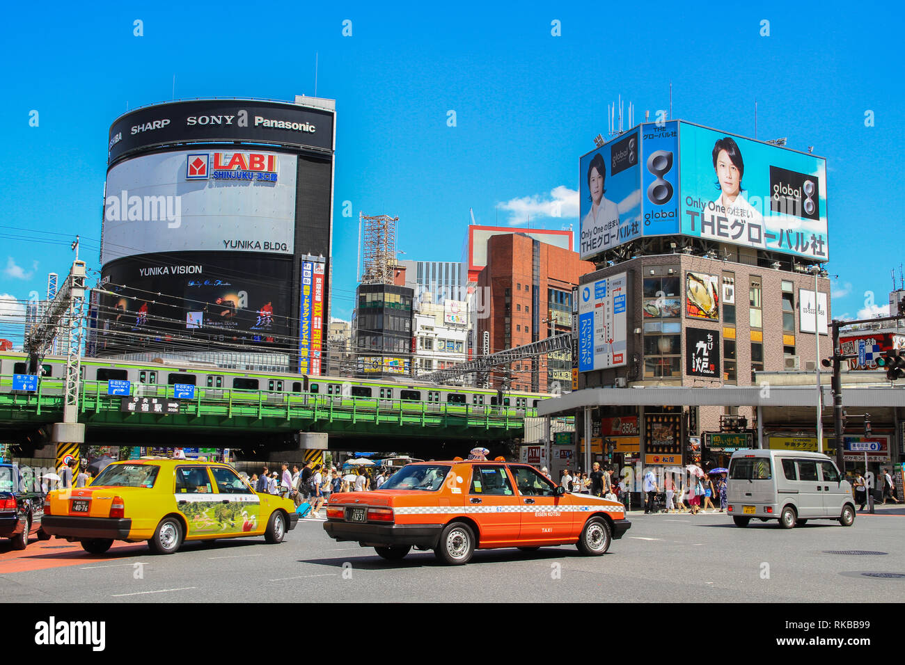 Intersección mostrando el inmenso tráfico de la megalópolis de Tokio, Japón, con coches, peatones, metro y enormes carteles publicitarios Foto de stock