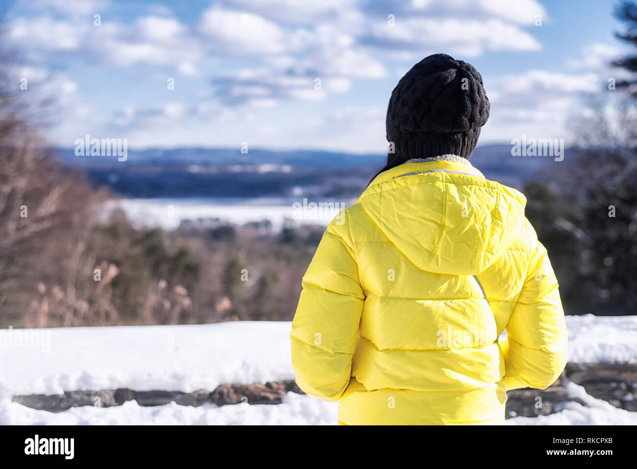 Una mujer vistiendo una chaqueta de invierno amarillo contemplando el  paisaje de las colinas que rodean los Berkshires de West Stockbridge  Massachusetts en un frío s Fotografía de stock - Alamy