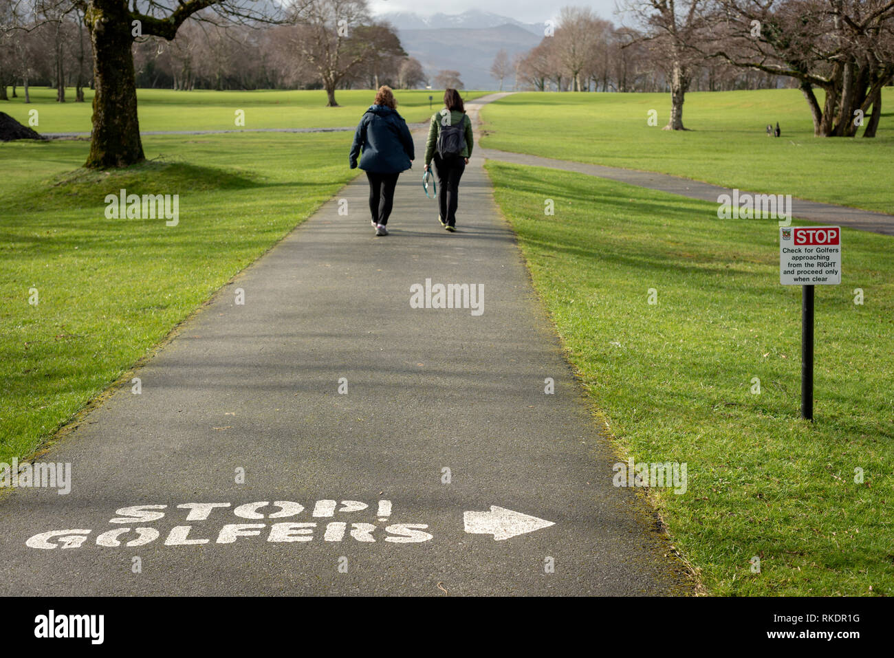 Dos mujeres caminando en el callejón del campo de golf. Campo de golf reglas cartel aviso de información. Club de golf y pesca de Killarney, Condado de Kerry, Irlanda. Foto de stock