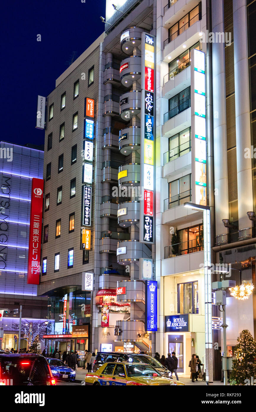 Ginza de Tokio, la noche. Tienda de Ibiza con su columna de semicírculo, balcones y el Royal Asscher almacenar los edificios. Los árboles de Navidad y luces en pavimento Foto de stock