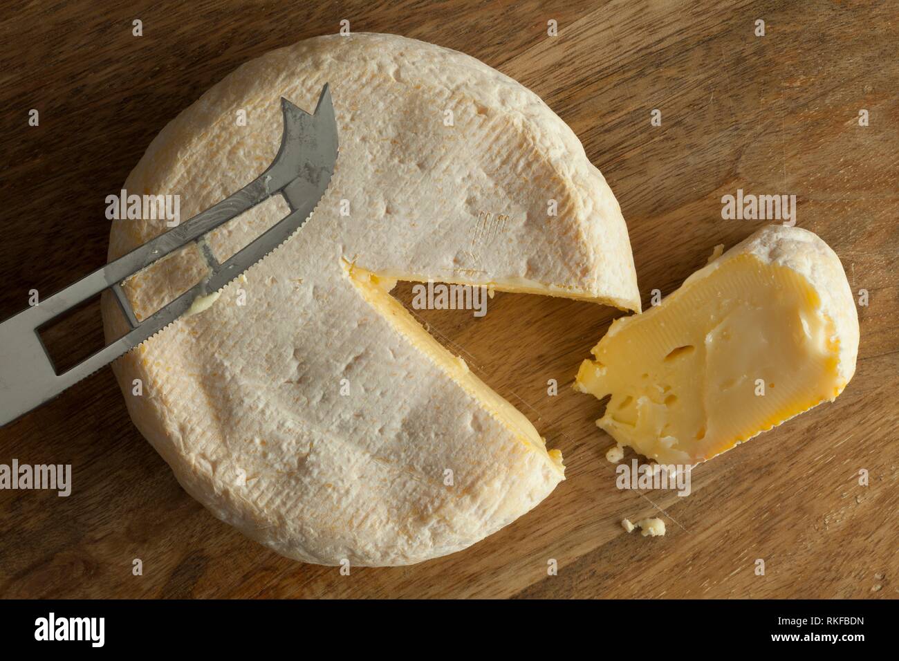 El Reblochon de Savoie queso de leche de vaca cruda con una rebanada. Foto de stock