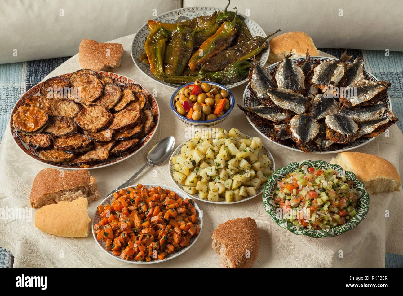 Comida marroquí con una variedad de platos con sardinas cocinadas frescas, verduras y pan. Foto de stock