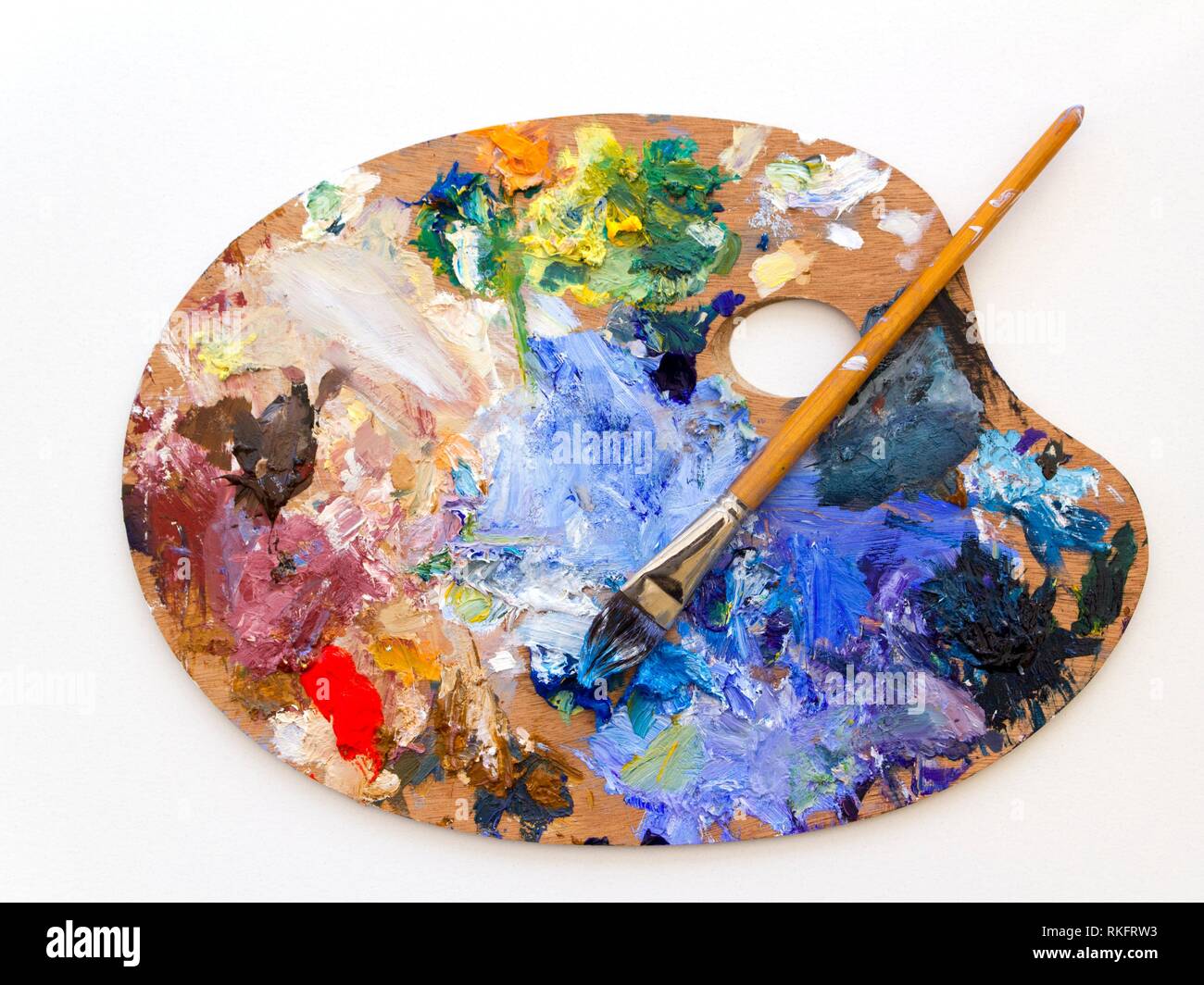 Artistas colorida paleta de pintura de aceite y cepillos de cerca sobre fondo liso. Foto de stock