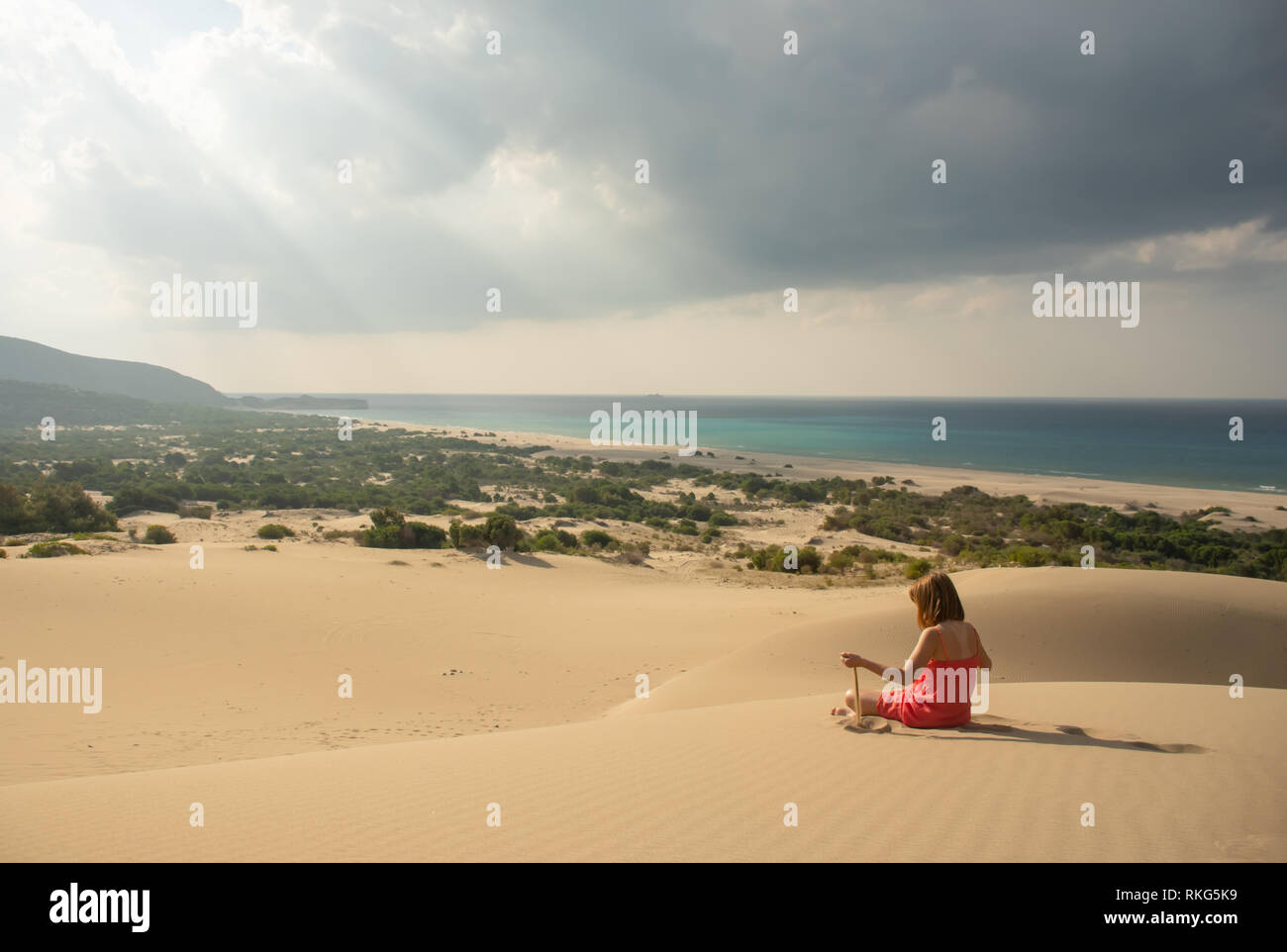 Chica en rojo relajante en el desierto de arena Foto de stock