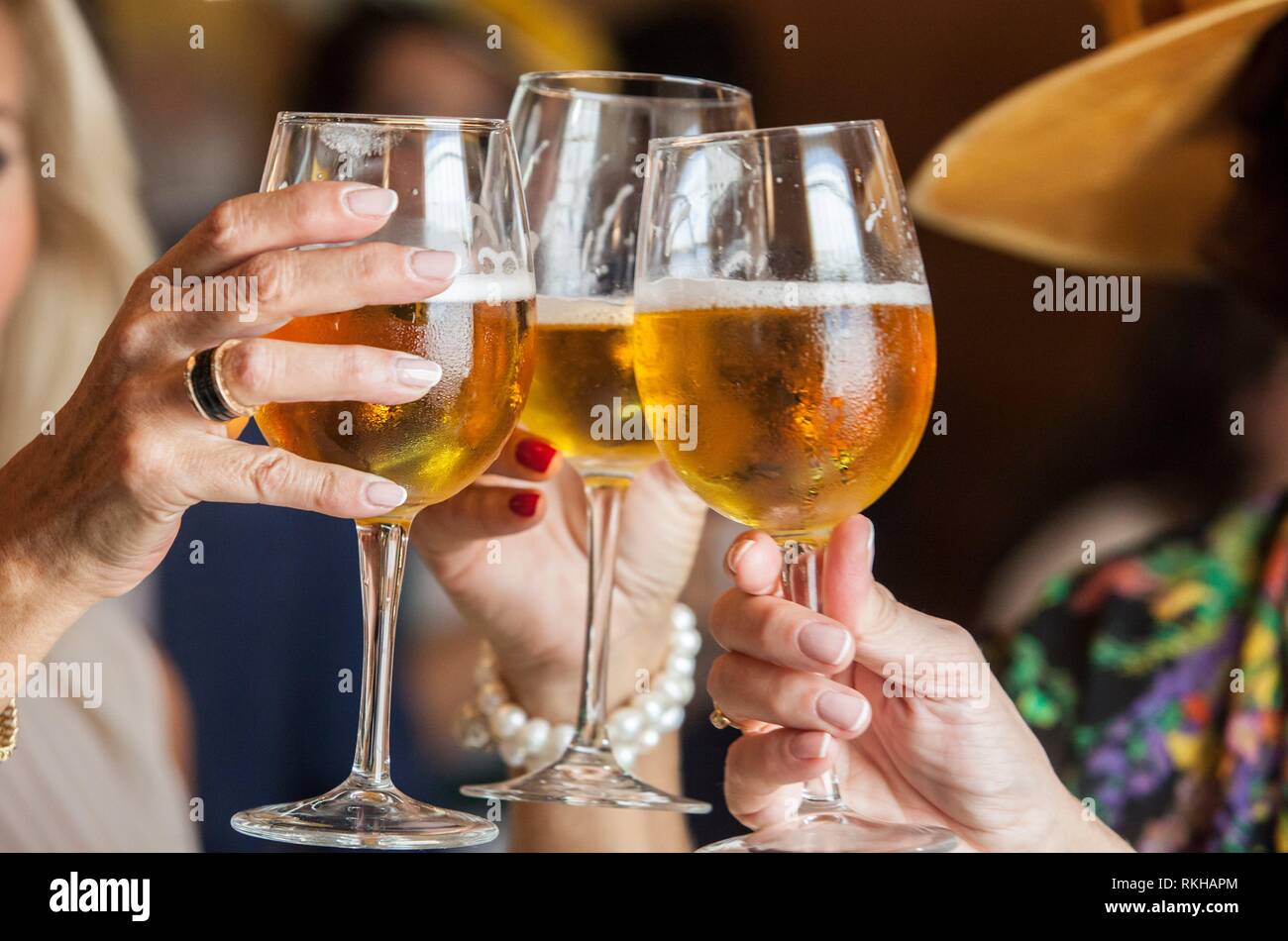 La gente en el cóctel de bienvenida que. Tres mujeres maduras beber un brindis con el cáliz de vidrio de cerveza. El enfoque selectivo. Foto de stock