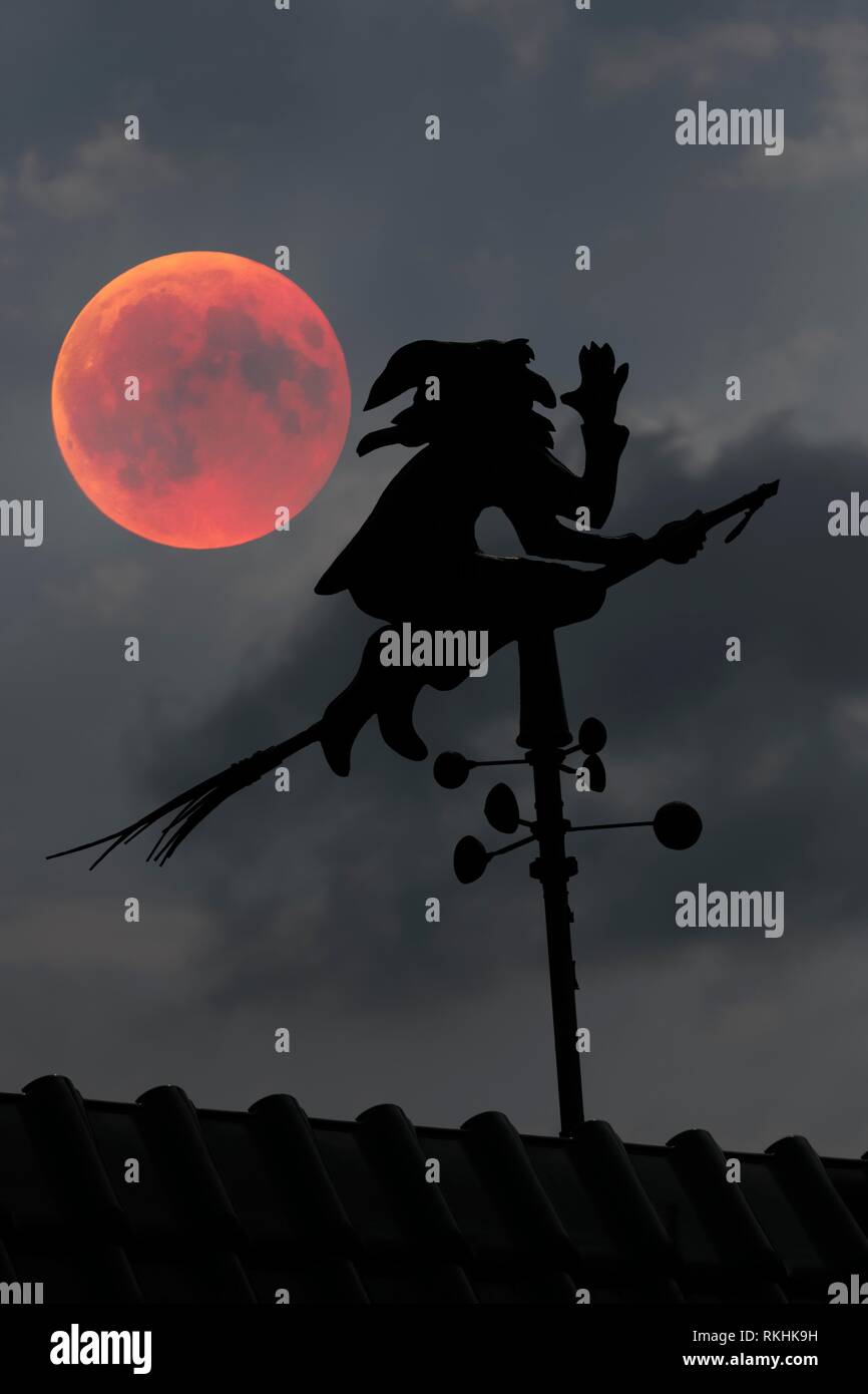 Luna de sangre sobre el tejado de una casa con veleta con weather witch, Baden-Württemberg, Alemania Foto de stock