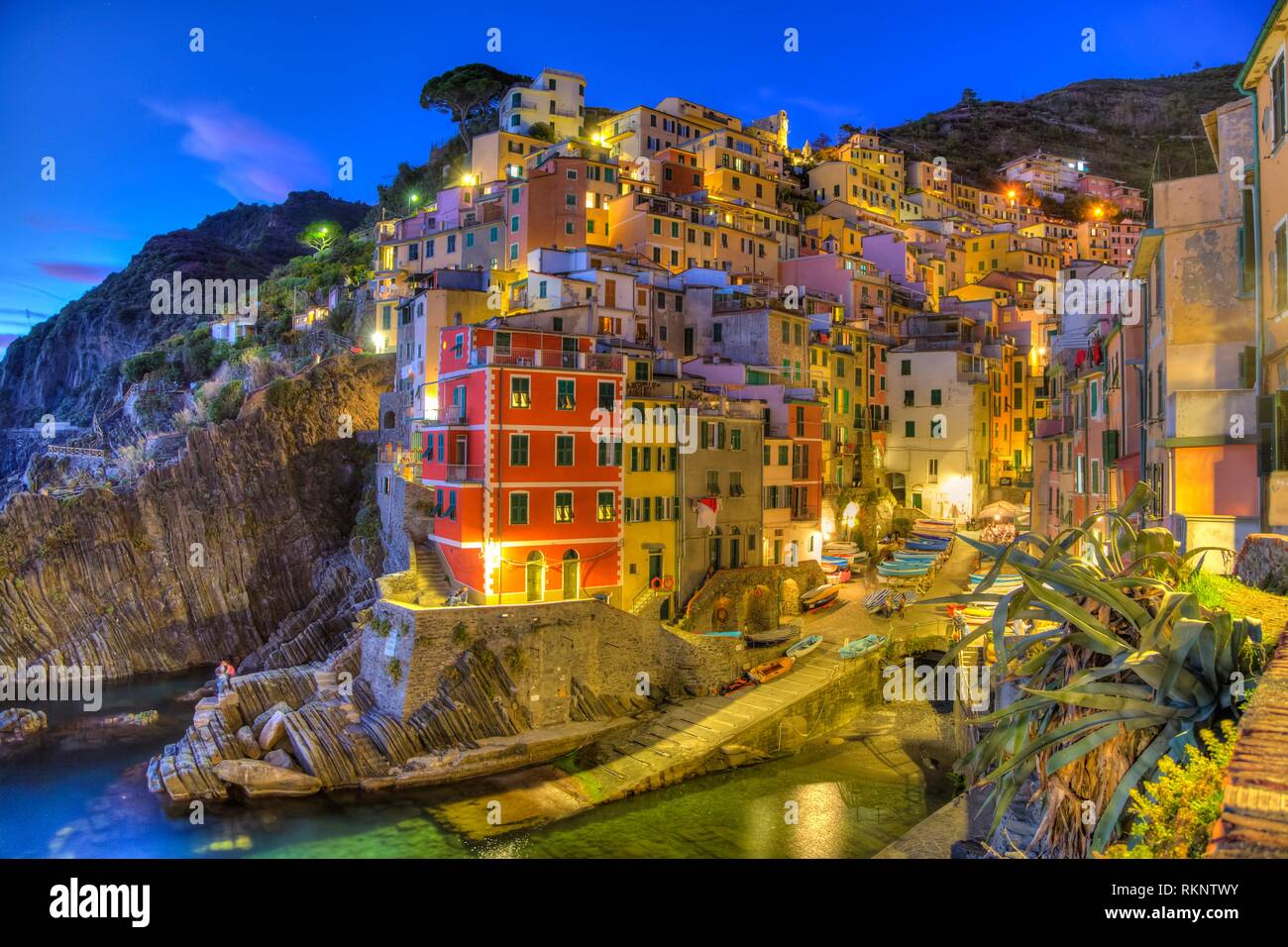 El Pueblo Acantilado de Riomaggiore iluminado al anochecer, en Cinque Terre, Italia, Europa. Foto de stock