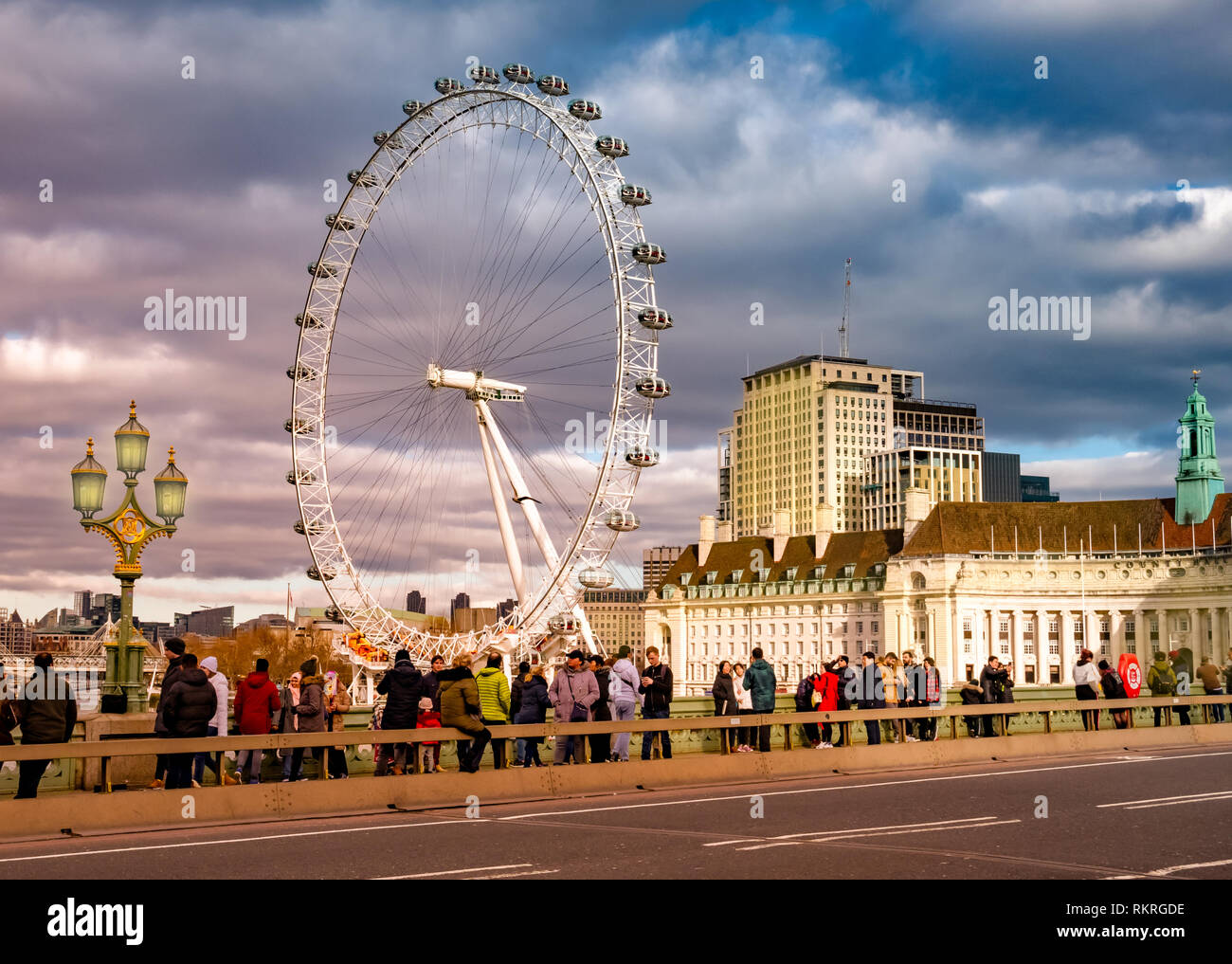 Londres, Reino Unido - 10 de enero de 2019: Los turistas que visitan Londres en frente del famoso ojo whell, entre el río Támesis iluminado por la luz del atardecer Foto de stock