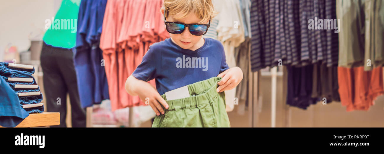 El niño intenta en la ropa en la tienda de ropa BANNER, largo de stock - Alamy
