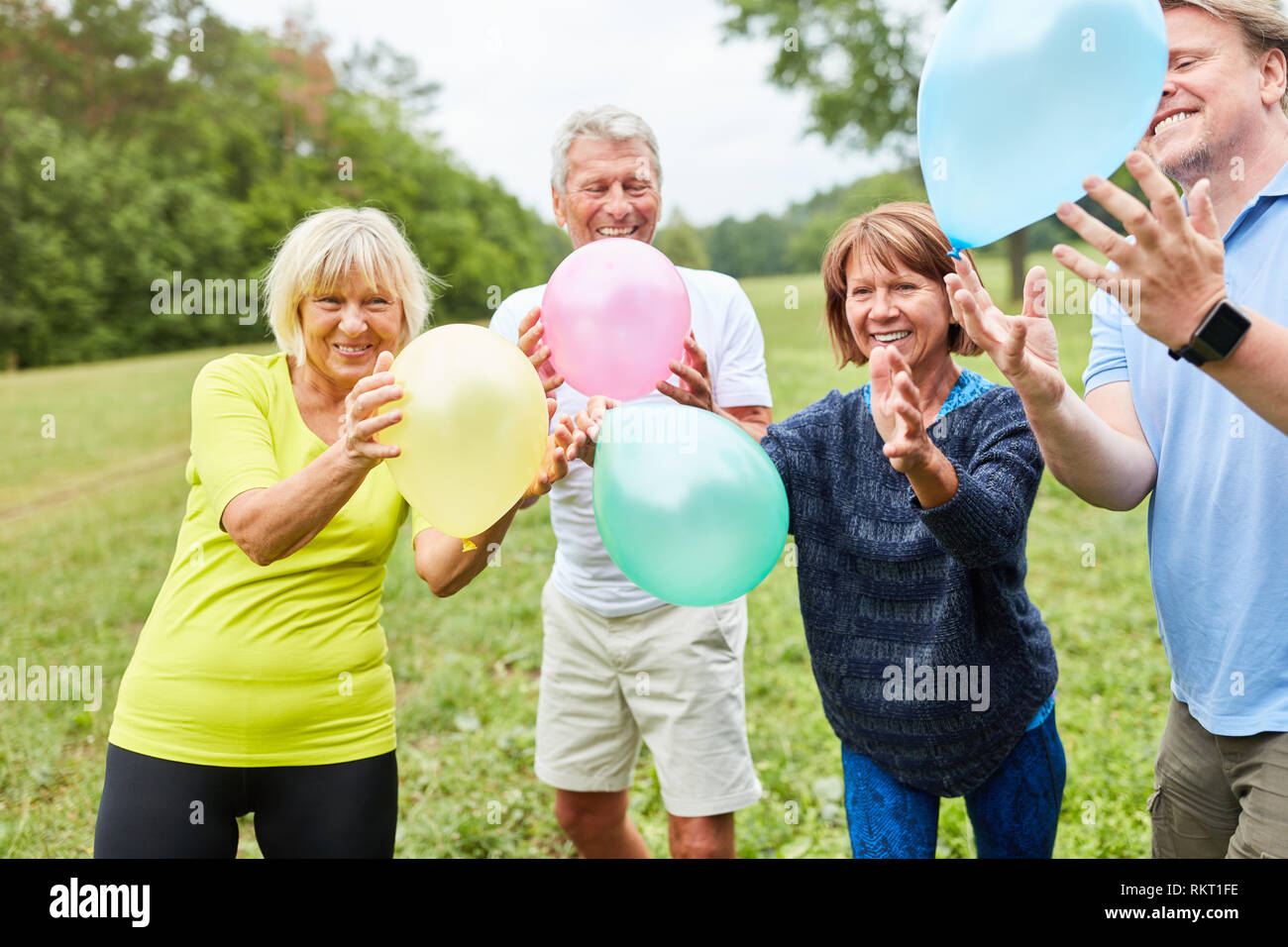 Alegre ancianos jugando con globos de colores en una fiesta de verano Foto de stock