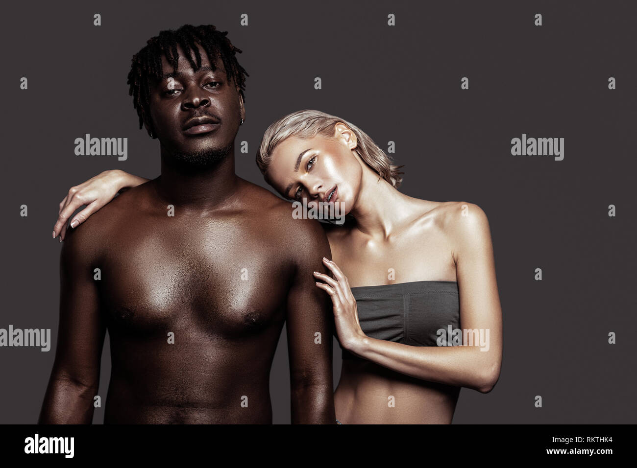 Par de modelos internacionales sentimiento ocupado mientras posan juntos Foto de stock