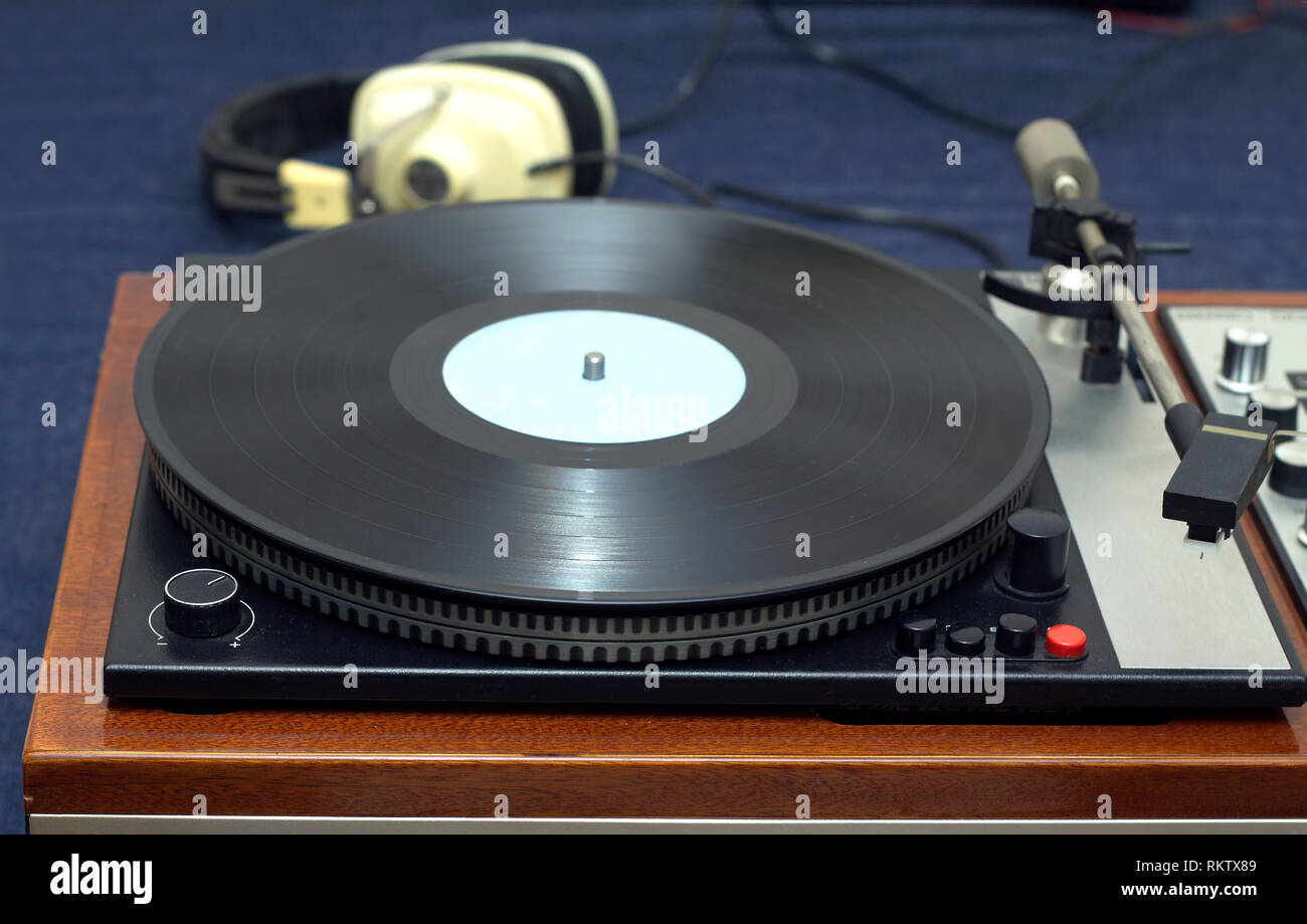 Estilo clásico analógico Vintage tocadiscos en caso de madera con un disco de vinilo con etiqueta azul y auriculares. Foto horizontal vista frontal closeup Foto de stock