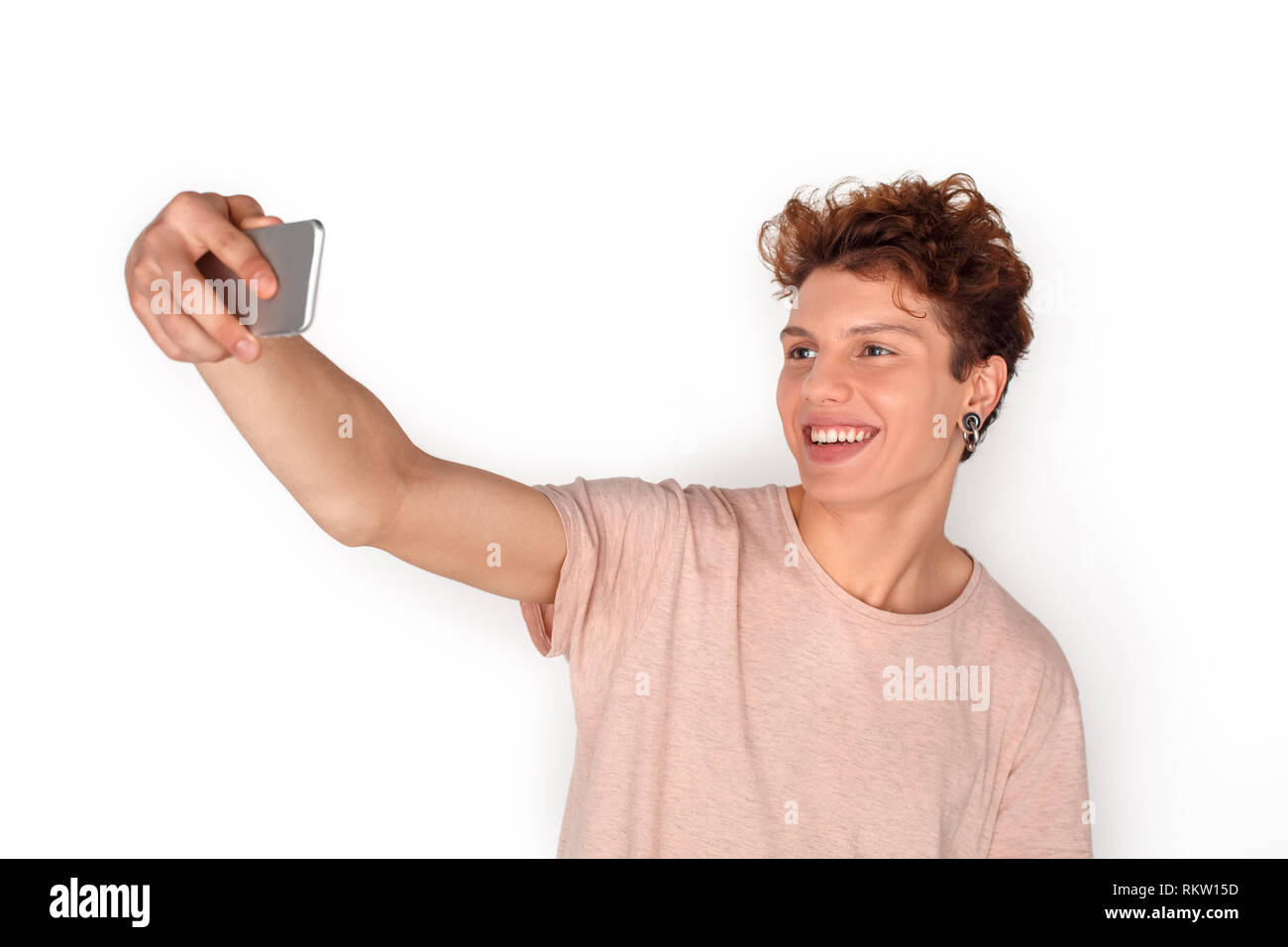 Adolescente niño usando aretes studio se encuentran aisladas en pared  blanca tomando fotos selfie en smartphone posando a cámara sonriendo feliz  Fotografía de stock - Alamy