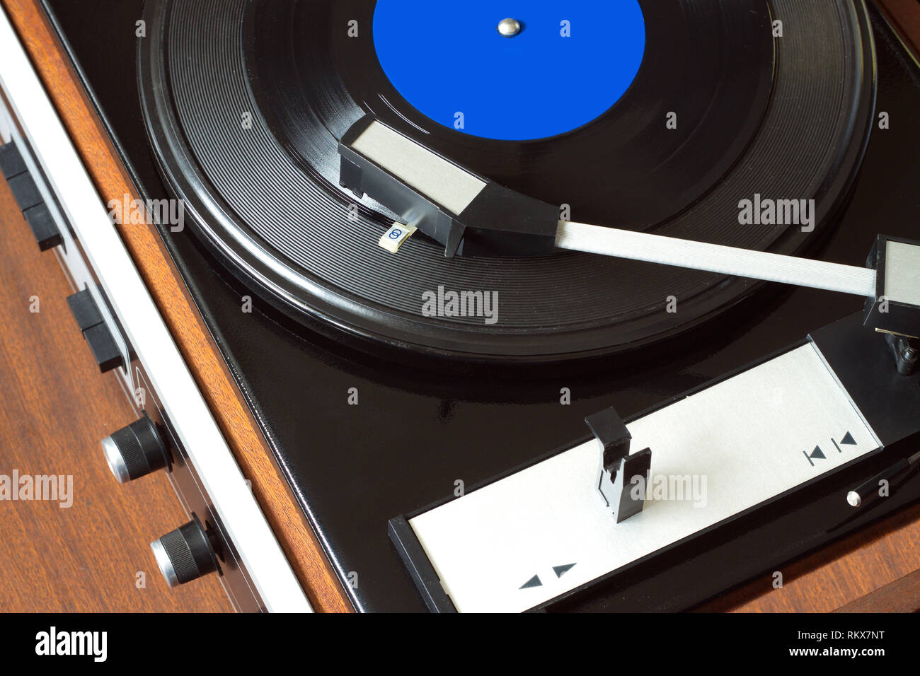 Vintage antiguo reproductor de discos de vinilo en caso de madera marrón tocando disco LP con etiqueta azul. Vista superior de la foto horizontal closeup Foto de stock