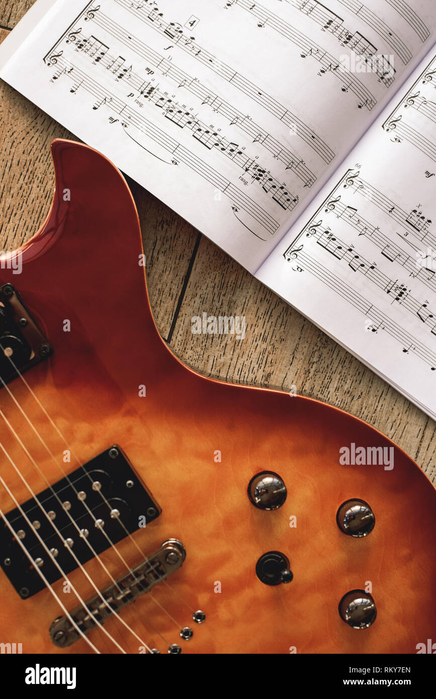 Los acordes de la guitarra eléctrica. La foto del cuerpo de la guitarra  eléctrica con control de volumen y tono perillas con notas musicales contra  el fondo de madera. Instrumentos musicales. Educación