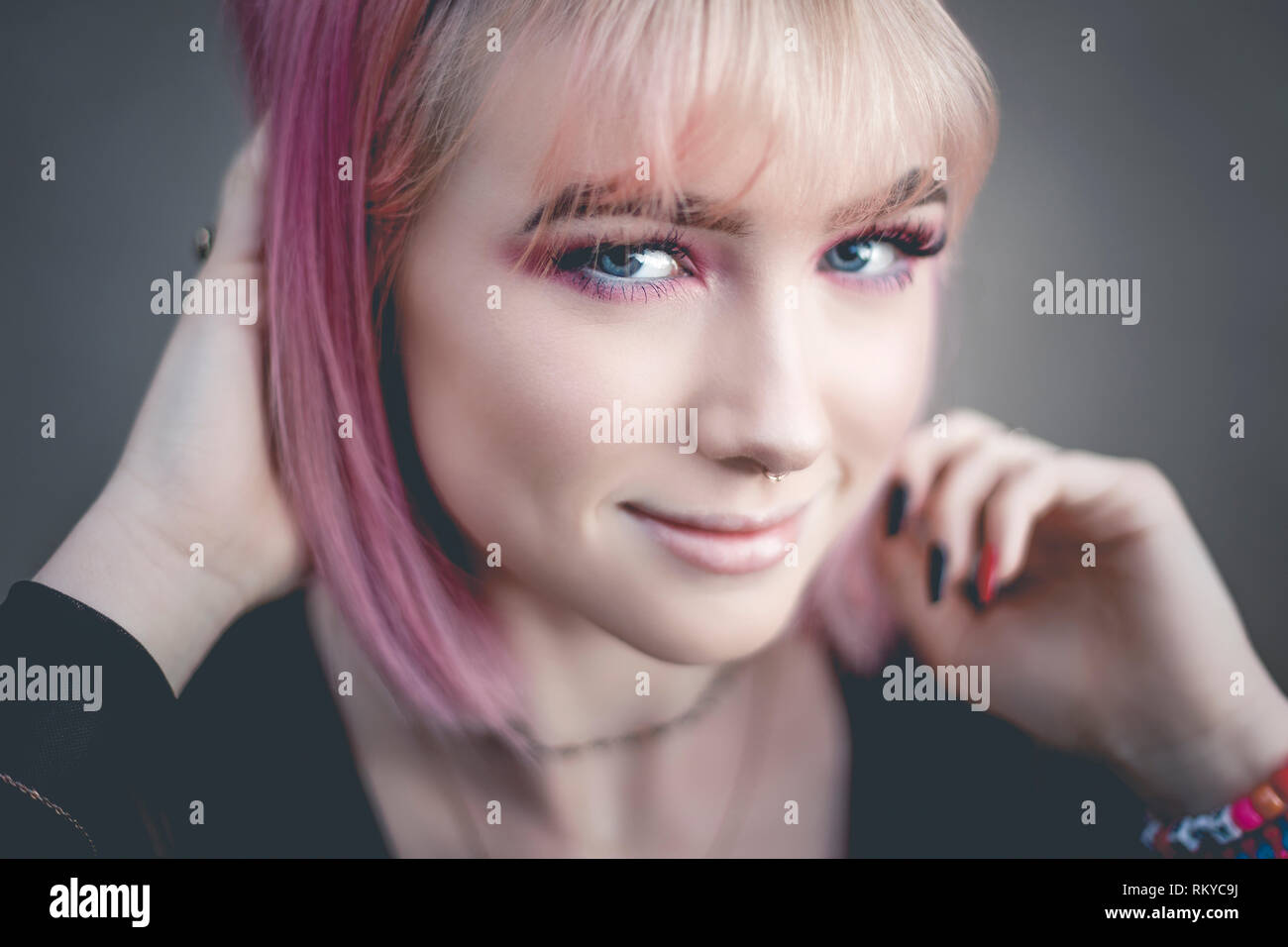 Retrato de jovencita con el pelo rosa y perforó la nariz mirando a la cámara. Foto de stock
