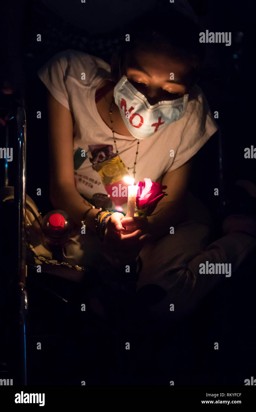 Mujer en silla de ruedas con cubre bocas y una vela rosa en sus manos. El 6 de julio de 2018, se celebró una vigilia en 25 ciudades de Colombia y el mundo Foto de stock