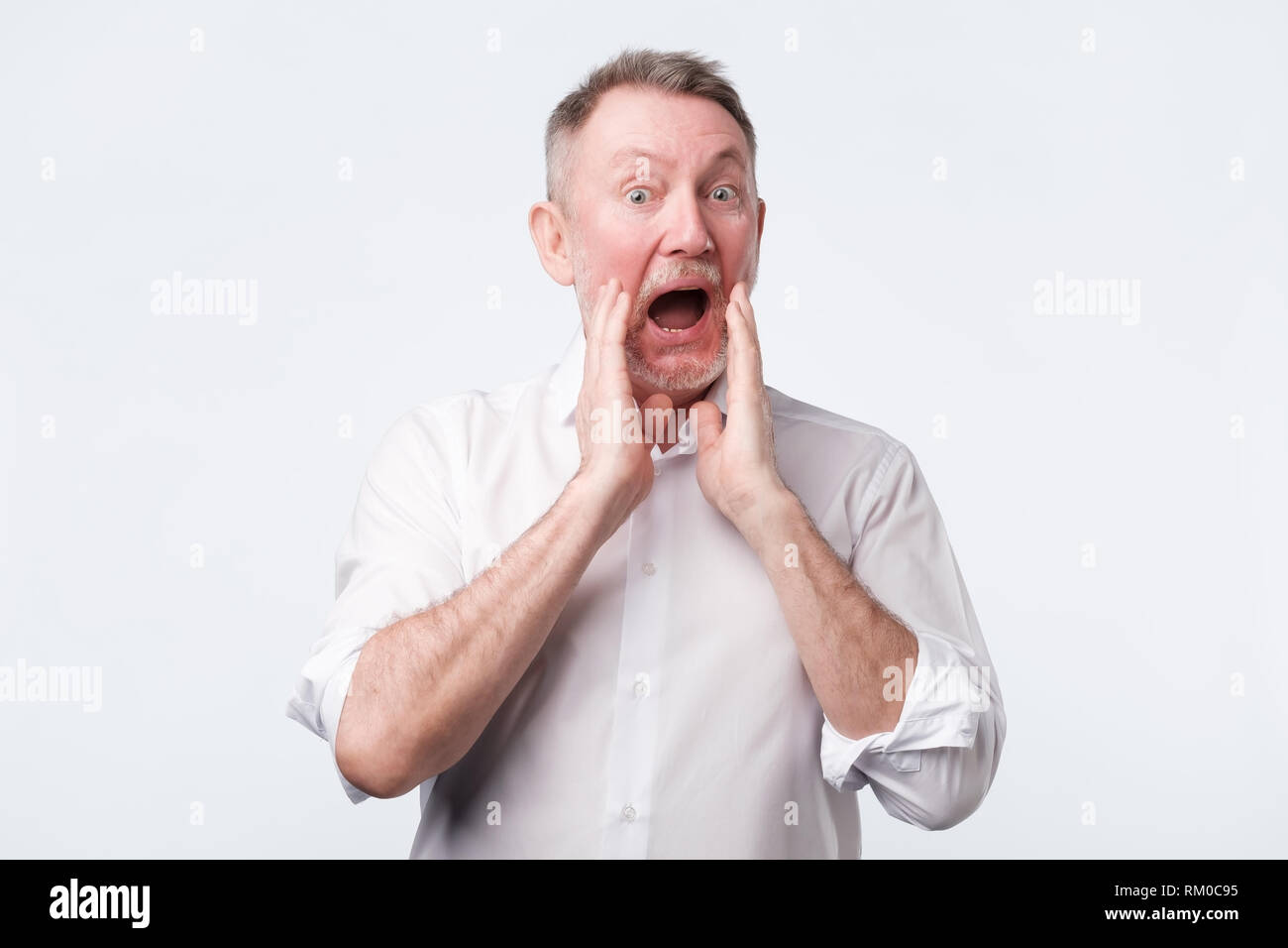 Hombre de europa senior en camisa blanca gritar algo Foto de stock