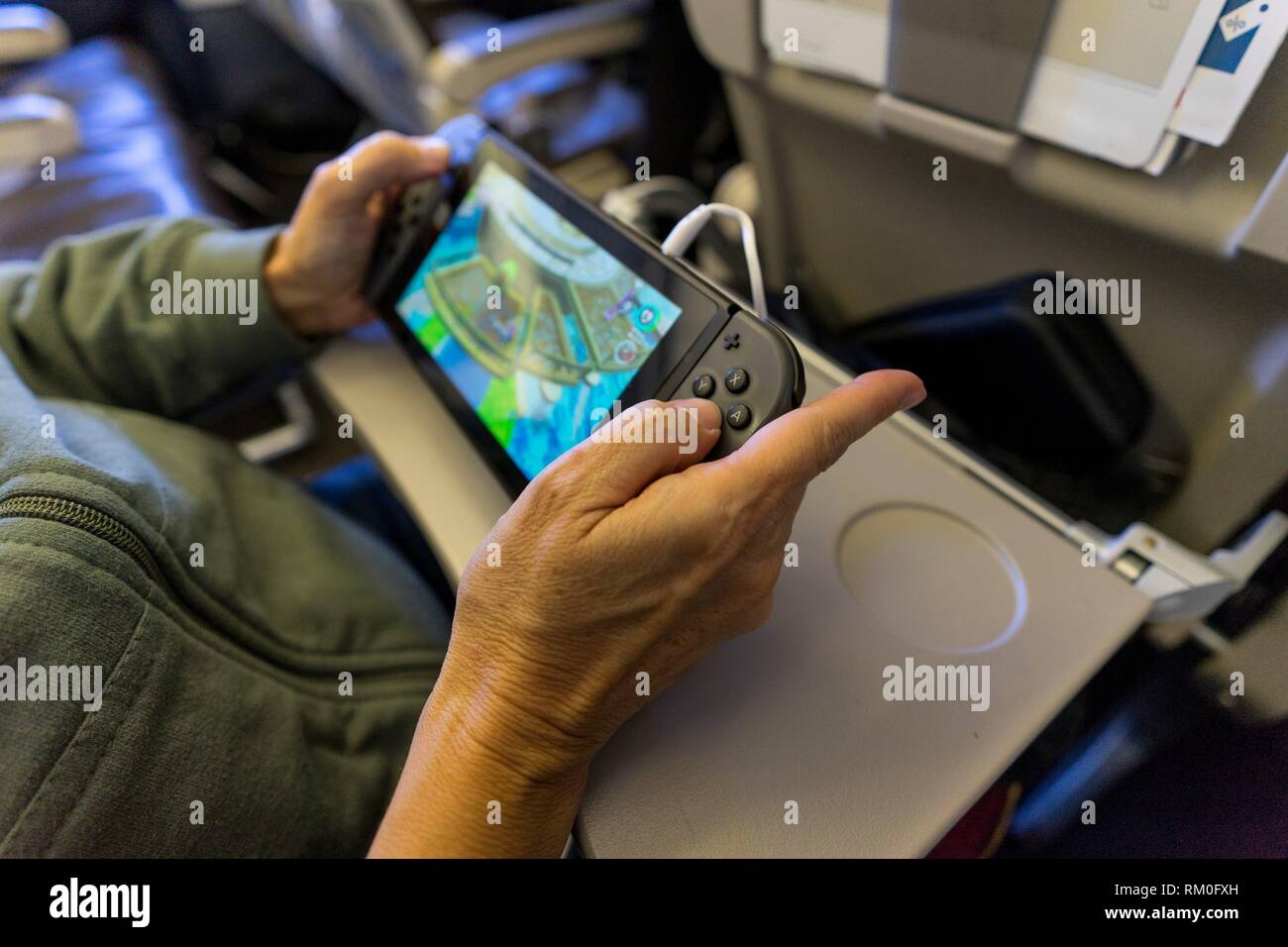 Mujer con la consola de juegos de bolsillo interior de avión Fotografía de  stock - Alamy