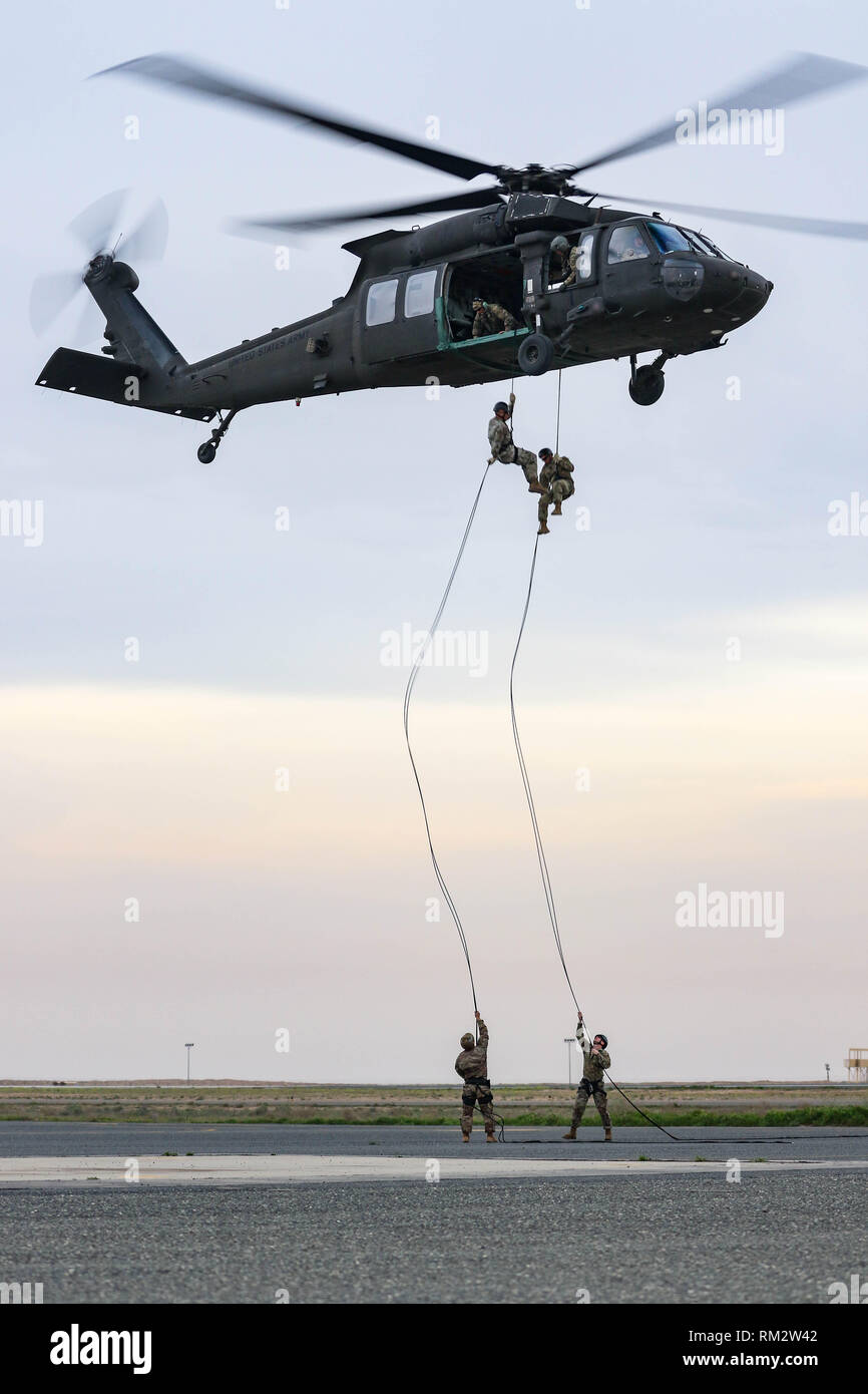 Dos soldados del Ejército de Estados Unidos repeler desde un helicóptero Black Hawk UH-60 Cuerda rápido durante la formación del sistema de inserción y extracción en la zona de aterrizaje Udairi, Camp Buehring, Kuwait, el 9 de febrero de 2019. Los instructores de la Guardia Nacional del Ejército Warrior Training Center, en Fort Benning, Georgia, entrenado y cualificado a la tripulación asignada al 1er Batallón del 108º Regimiento de Aviación, la Guardia Nacional del Ejército de Kansas, en preparación para un asalto del aire durante este mes. La foto es borrosa para proteger la seguridad operacional. (Ee.Uu. Foto de la Guardia Nacional del Ejército por el sargento. Emily Finn) Foto de stock